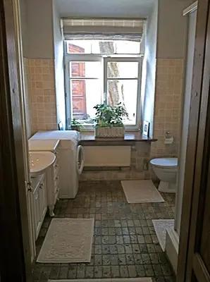 a bathroom with a sink and a toilet and a window at Pilies Apartments in Vilnius