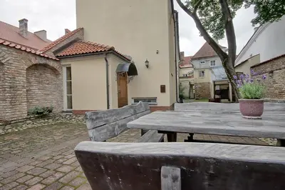 a wooden table and bench in a courtyard with a house at Pilies Apartments in Vilnius