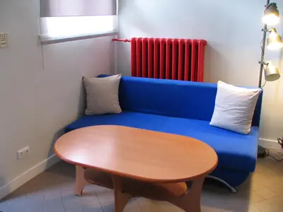 a blue couch with a wooden table and a red radiator at Studio 59 in Kaunas