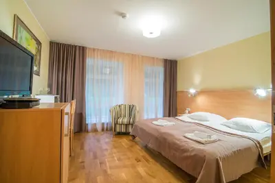 a hotel room with a bed and a flat screen tv at Guest House Milda in Druskininkai