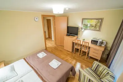 a small room with a bed and a television at Guest House Milda in Druskininkai