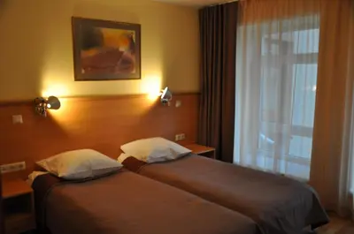 two beds in a hotel room with a window at Guest House Milda in Druskininkai