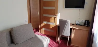 a room with two chairs and a desk and a television at Hotel Dainava in Druskininkai