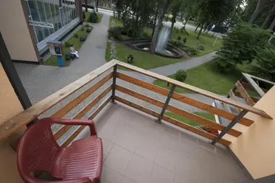 a balcony with a red chair and a park at Hotel Dainava in Druskininkai