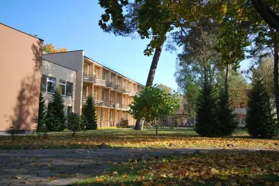 a building on a campus with leaves on the ground at Hotel Dainava in Druskininkai