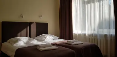 a bed with two towels on it with a window at Hotel Dainava in Druskininkai