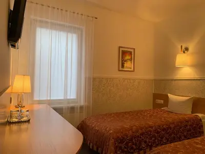 a bedroom with a bed and a table and a window at Broliu Vila in Druskininkai