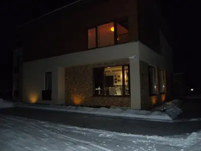 a building at night with snow in front of it at Broliu Vila in Druskininkai