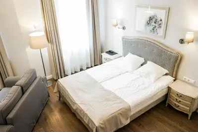 a bedroom with a white bed and a couch at Guest House Senasis Pastas in Druskininkai