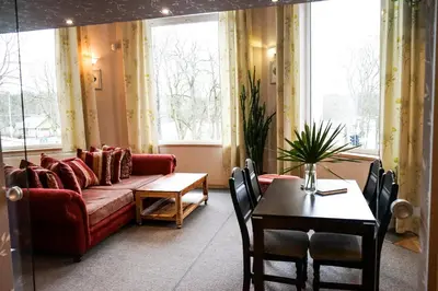 a living room with a red couch and a table at Guest House Senasis Pastas in Druskininkai