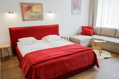 a bedroom with a red bed and a couch at Guest House Senasis Pastas in Druskininkai
