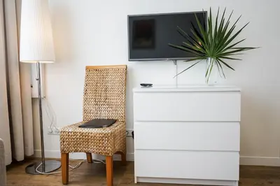 a room with a dresser and a chair and a tv at Guest House Senasis Pastas in Druskininkai