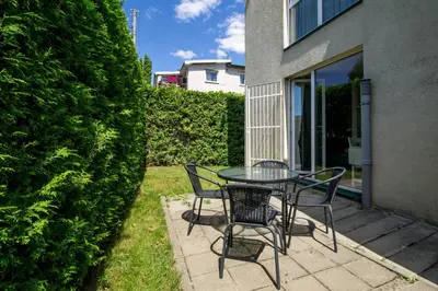 a patio with a table and chairs and a hedge at Cozy Garden Free parking in Vilnius