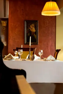 a table with wine glasses and a lamp on it at Harmony Park Hotel & SPA in Prienai