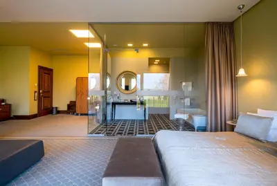 a bedroom with a bed and a bathroom with a mirror at Harmony Park Hotel & SPA in Prienai