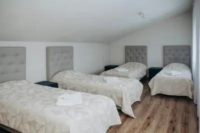 three beds in a room with white walls and wooden floors at Verslo Klasė-easy to stay in Panevėžys