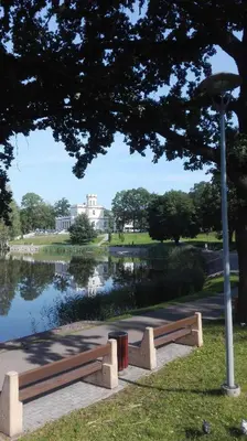 a park bench next to a lake with a building at Butas Vilniaus alėjoje in Druskininkai