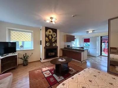 a living room with a table and a kitchen at Nakvisa in Zarasai