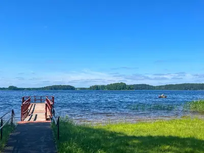 a dock on a lake with a boat in the water at Salako svečių namai in Salakas