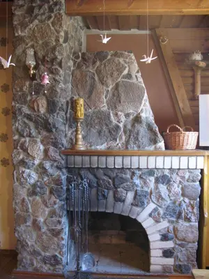 a stone fireplace in a living room with stars on the wall at Salako svečių namai in Salakas