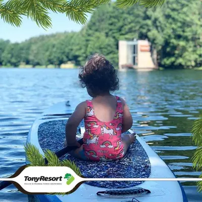 a little girl sitting on a paddle board in the water at TonyResort in Trakai