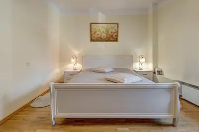 a white bed in a room with two night stands at Vidos apartamentai 2 in Vilnius