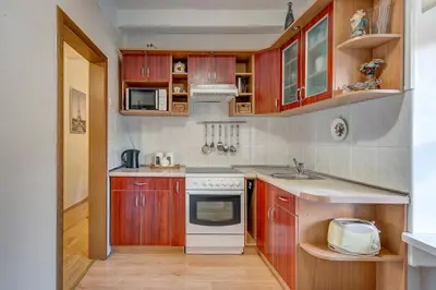 a kitchen with wooden cabinets and a white stove top oven at Vidos apartamentai 2 in Vilnius