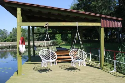 two chairs on a dock with a gazebo at Kaimo turizmo sodyba 