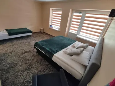a bedroom with a bed and a couch and two windows at Kaimo turizmo sodyba 