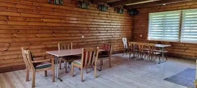 a dining room with tables and chairs in a log cabin at Kaimo turizmo sodyba 