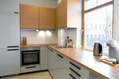 a kitchen with wooden cabinets and a sink and a window at Kaunas Old Town Apartment in Kaunas
