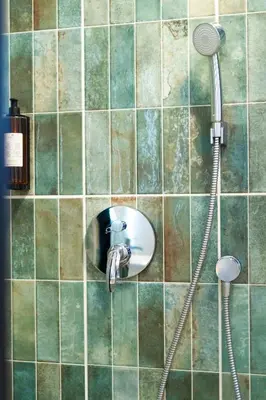 a shower with a faucet on a tiled wall at Kaunas Old Town Apartment in Kaunas