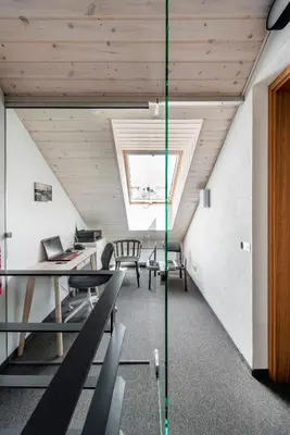 an attic office with tables and chairs and a window at Piano Apartments in Kaunas