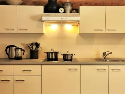 a kitchen with white cabinets and two pots on a stove at Aliai in Utena