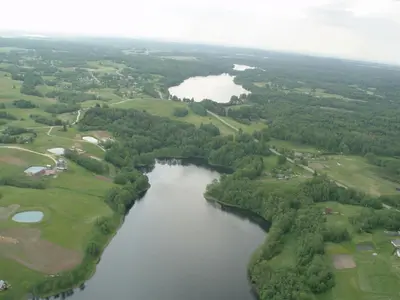 an aerial view of a river with golf courses and trees at Aliai in Utena