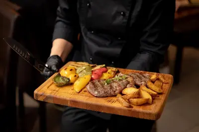 a person holding a cutting board with steak and fries at Butenas Hotel Tyla in Biržai