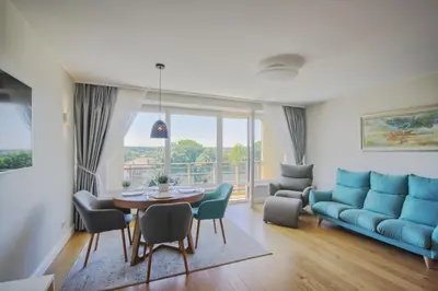 a living room with a blue couch and a table and chairs at Penthouse in Druskininkai