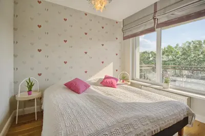 a bedroom with a bed with pink pillows and a window at Penthouse in Druskininkai