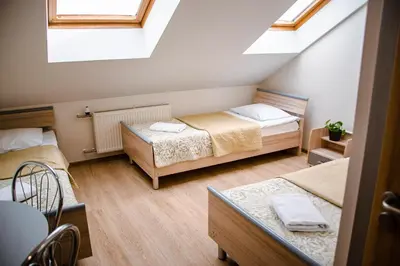 a attic room with two beds and a window at Hotel Pas Katina in Panevėžys