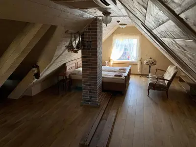 a attic room with a bed and a window at Arbatinės apartamentai in Biržai