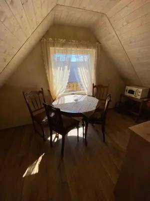 a dining room with a table and chairs in a attic at Arbatinės apartamentai in Biržai