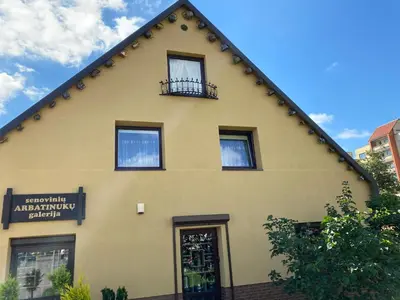 a yellow building with a gambrel roof at Arbatinės apartamentai in Biržai