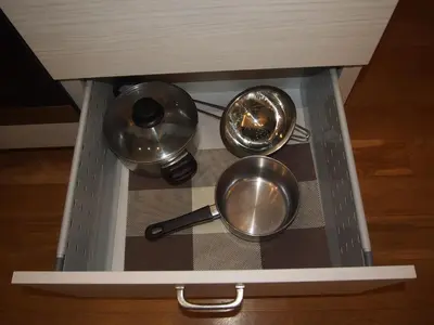 a drawer with three pots and pans in a cabinet at Teatro Apartments in Vilnius