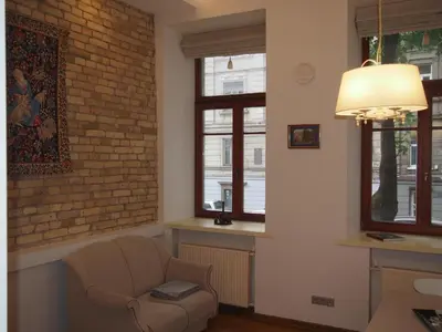 a living room with a chair and a brick wall at Teatro Apartments in Vilnius