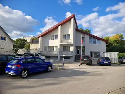 a building with cars parked in a parking lot at Pasile in Kaunas