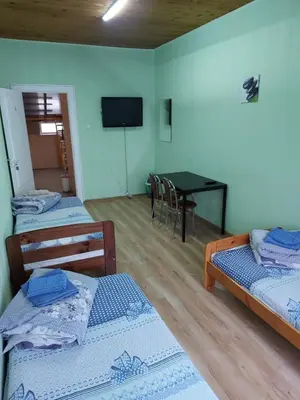 a room with three beds and a table with a television at Pasile in Kaunas