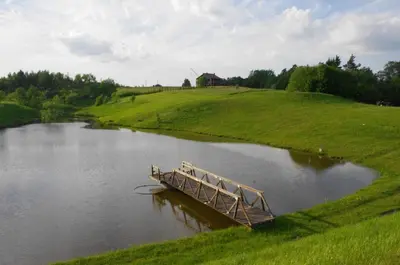 a wooden bridge in the middle of a river at Rasos sodyba in Prienai