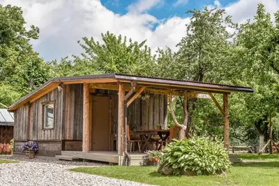 a wooden cabin with a table in the grass at Rasos sodyba in Prienai