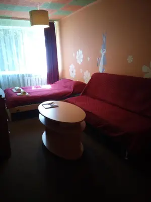 a bedroom with two beds and a table and a window at Nakvynė Anykščių centre in Anykščiai