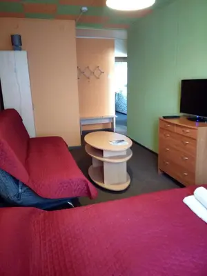 a room with two beds and a table and a tv at Nakvynė Anykščių centre in Anykščiai